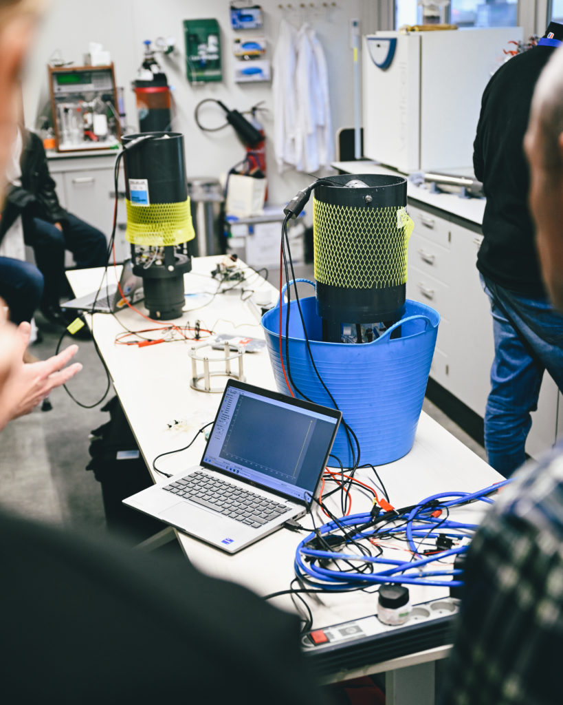 Picture of the sensor on top of a desk, with wires attached to it, and with a computer on the side. 