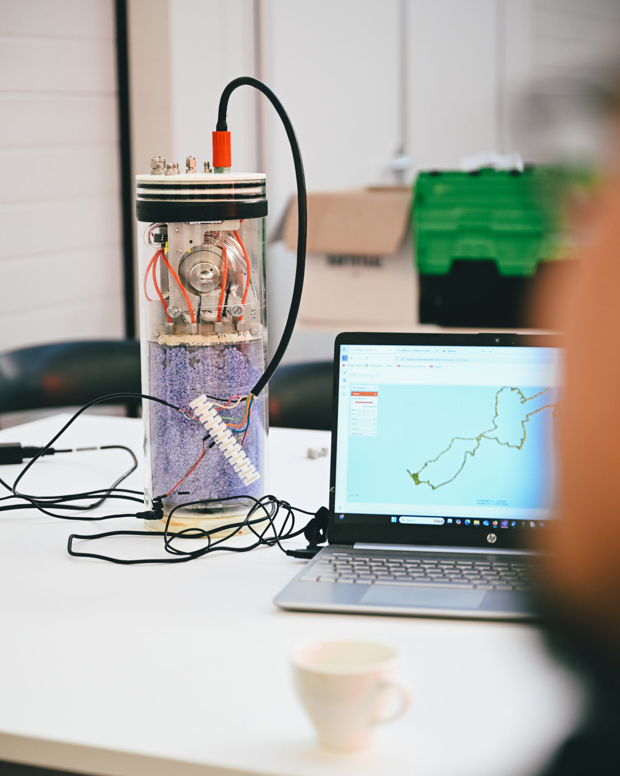 The CaPASOS instrument on a desk next to a computer that shows its route at sea