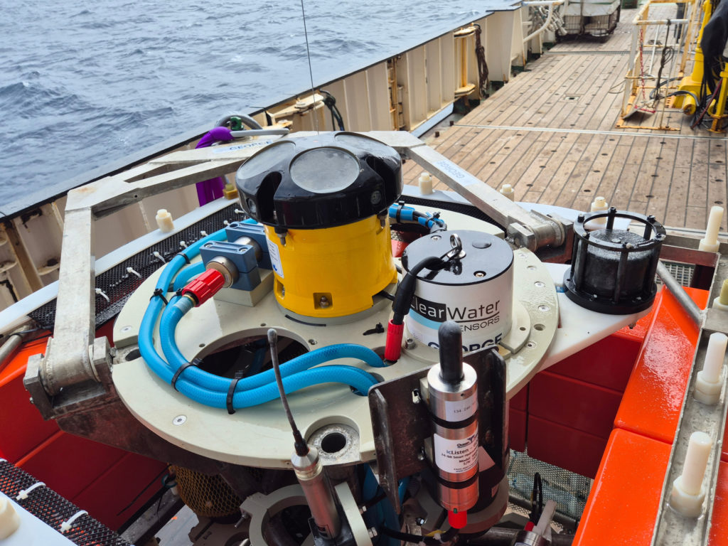 Blue tubing and sampling containers inside an ocean monitoring instrument prepared for deployment at sea.