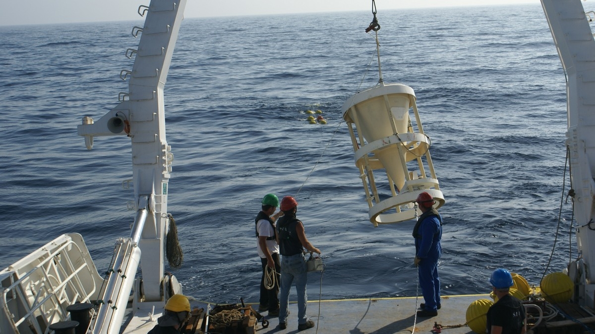 picture of an instrument being lowered onto sea from a ship with a large crane